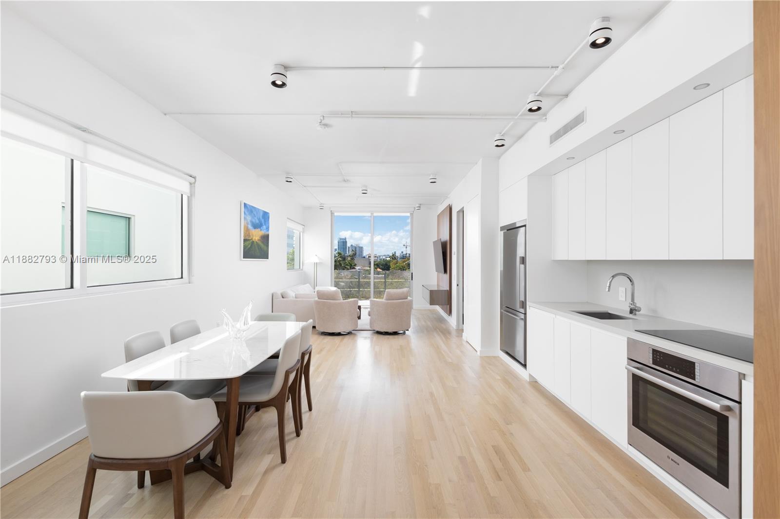 1700 Meridian Avenue, Unit 406 Miami Beach, FL 33139 - Photo 9 of 36 a kitchen with stainless steel appliances a dining table chairs and sink