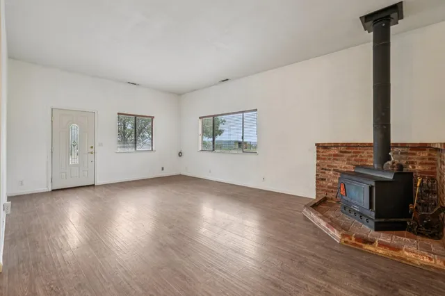 a view of an empty room with window and a kitchen