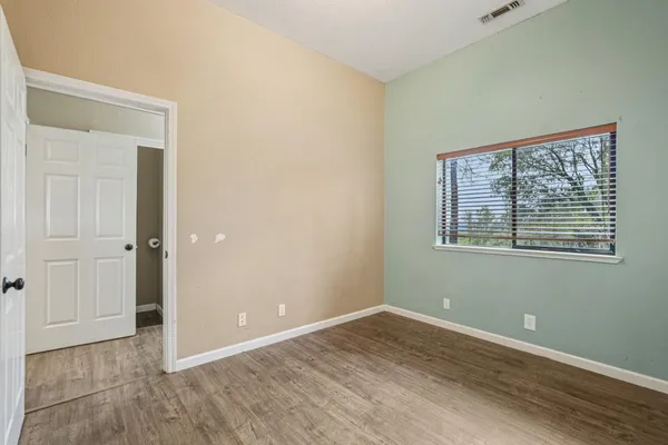 an empty room with wooden floor and mirror