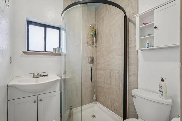 an empty room with wooden floor chandelier fan and windows