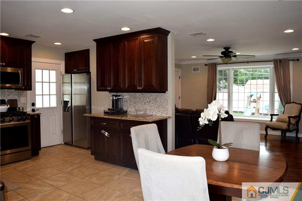 10 Fordham Road Old Bridge, NJ 08859 - Photo 4 of 26 a kitchen with stainless steel appliances granite countertop a stove top oven a sink dishwasher a dining table and chairs with wooden floor