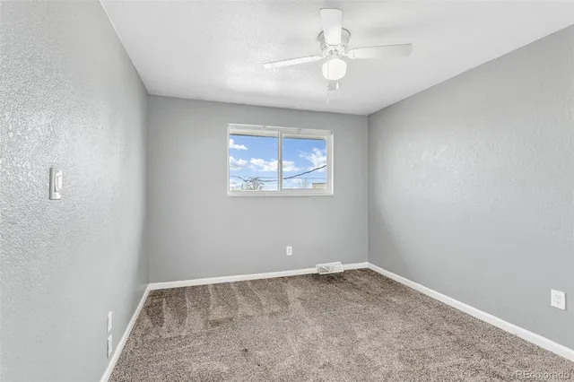 an empty room with a chandelier fan and windows