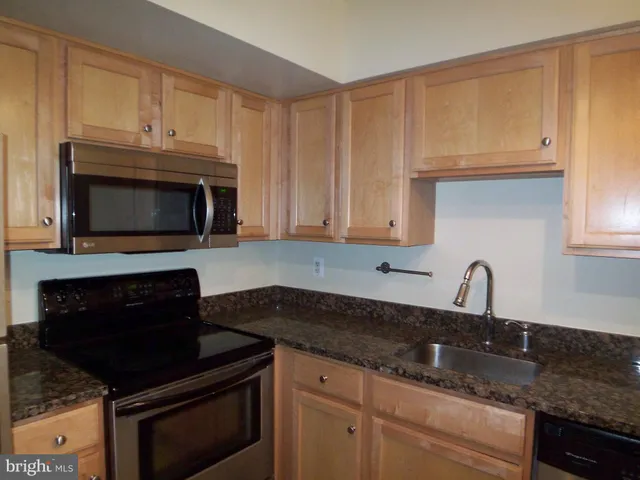 a kitchen with granite countertop white cabinets and stainless steel appliances