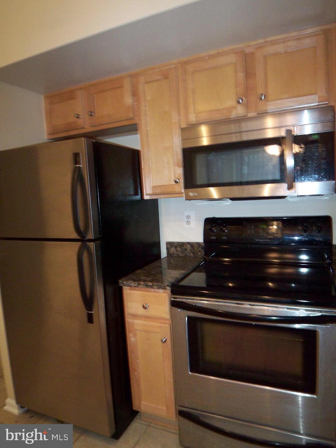 1001 North Randolph Street, Unit 516 Arlington, VA 22201 - Photo 6 of 18 a kitchen with granite countertop white cabinets and stainless steel appliances