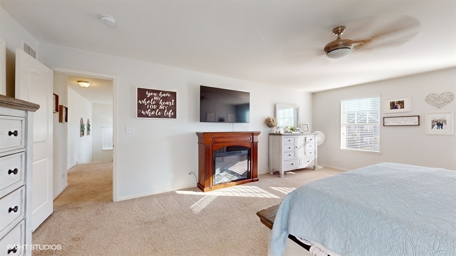 25613 West Cerena Circle Plainfield, IL 60586 - Photo 11 of 28 a spacious bedroom with a fireplace and a ceiling fan