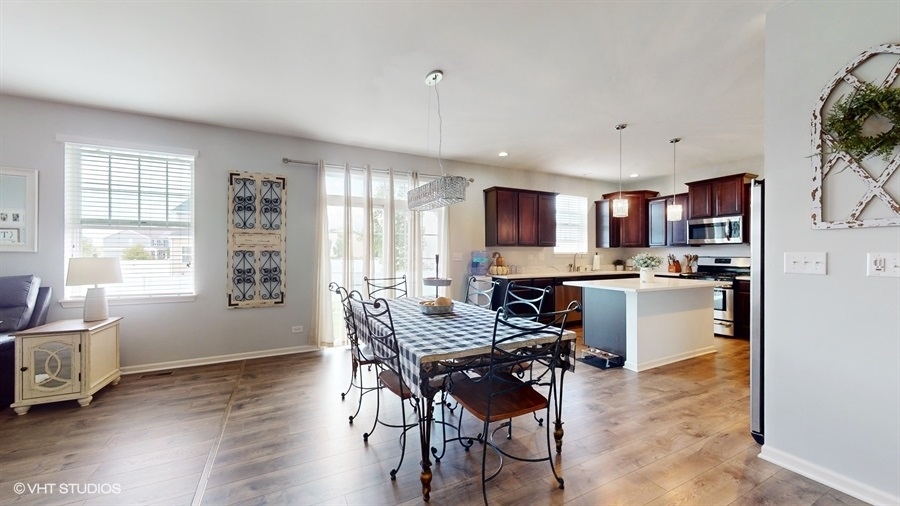 25613 West Cerena Circle Plainfield, IL 60586 - Photo 4 of 28 a kitchen with kitchen island a dining table chairs and a wooden floor