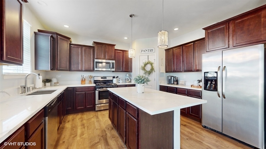 25613 West Cerena Circle Plainfield, IL 60586 - Photo 5 of 28 a kitchen with a sink a stove a refrigerator and cabinets