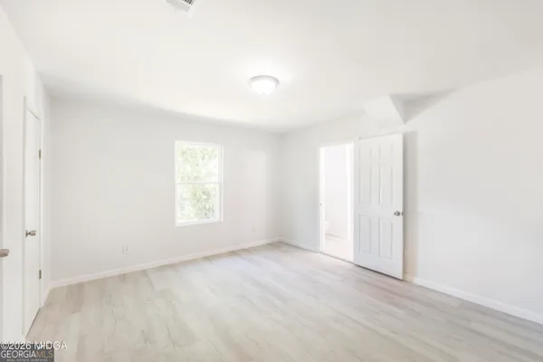 a view of an empty room with wooden floor and window