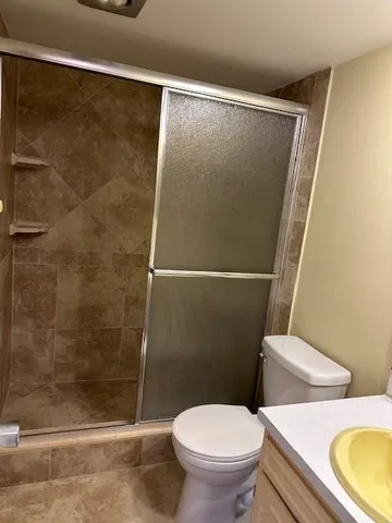 a white toilet sitting next to a shower
