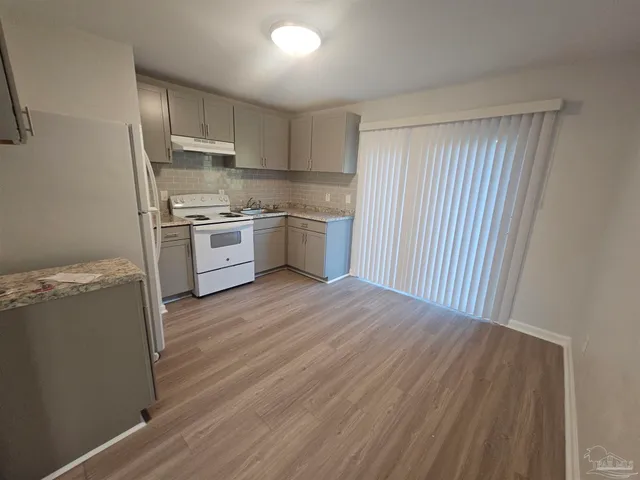 a kitchen with a refrigerator stove and wooden floor