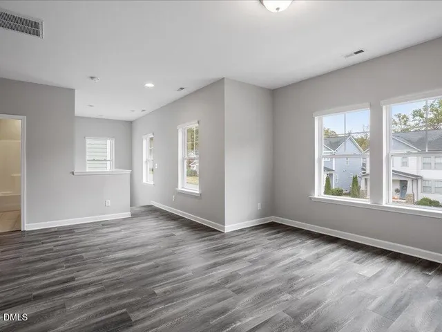 a view of an empty room with wooden floor and closet