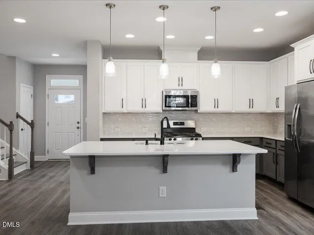 a kitchen with kitchen island stainless steel appliances a sink a refrigerator and cabinets