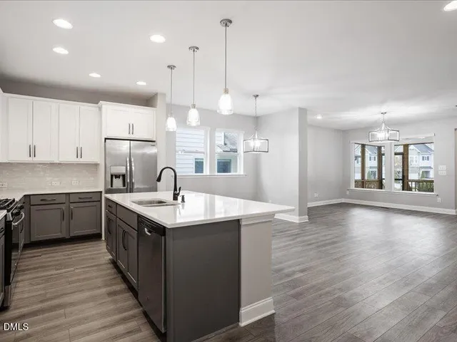 a kitchen with stainless steel appliances granite countertop a refrigerator a sink dishwasher a stove and white cabinets with wooden floor