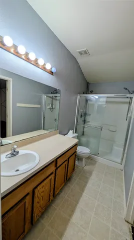 a spacious bathroom with a granite countertop sink a toilet a mirror and shower