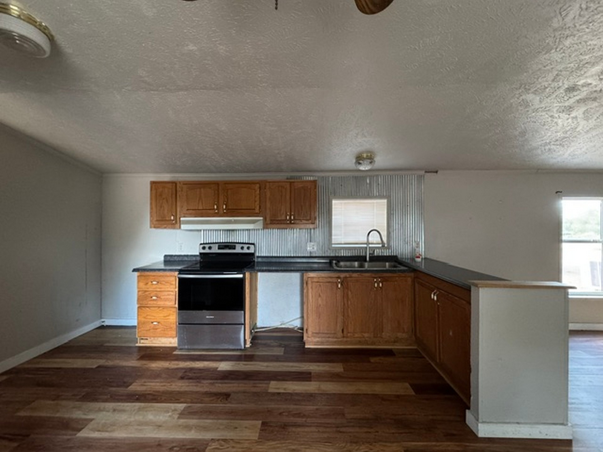 109558 South 4760 Road Muldrow, OK 74948 - Photo 13 of 22 Kitchen featuring wood-finish flooring, wood cabinetry, dark countertops, and a corrugated metal backsplash