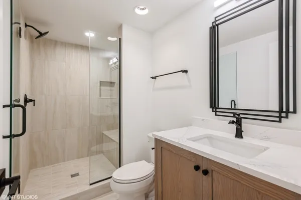 a bathroom with a shower sink vanity mirror and toilet