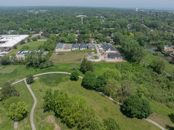 an aerial view of residential houses with outdoor space and trees