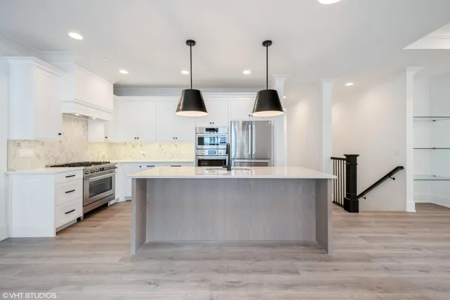 a kitchen with stainless steel appliances granite countertop a sink a stove and a wooden floors