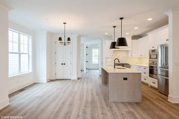 a kitchen with stainless steel appliances a stove top oven a sink a refrigerator and a window