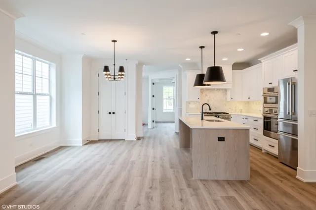 a kitchen with stainless steel appliances a stove top oven a sink a refrigerator and a window