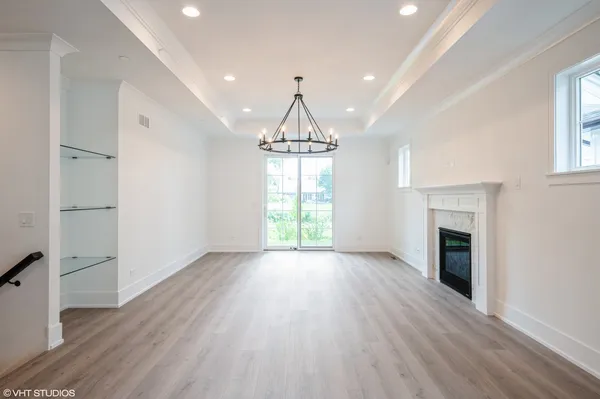an empty room with wooden floor fireplace and windows