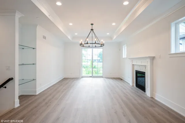 an empty room with wooden floor fireplace and windows