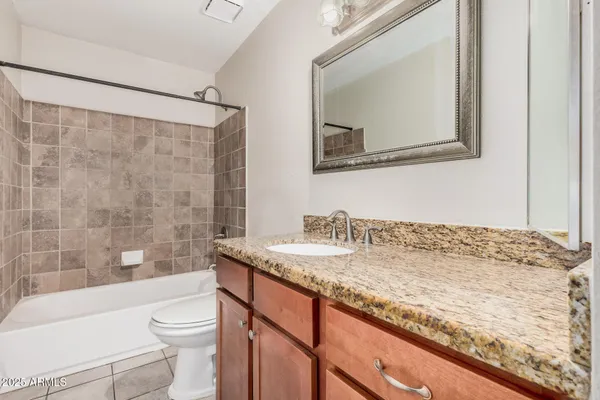 a bathroom with a granite countertop sink a toilet a mirror and bathtub
