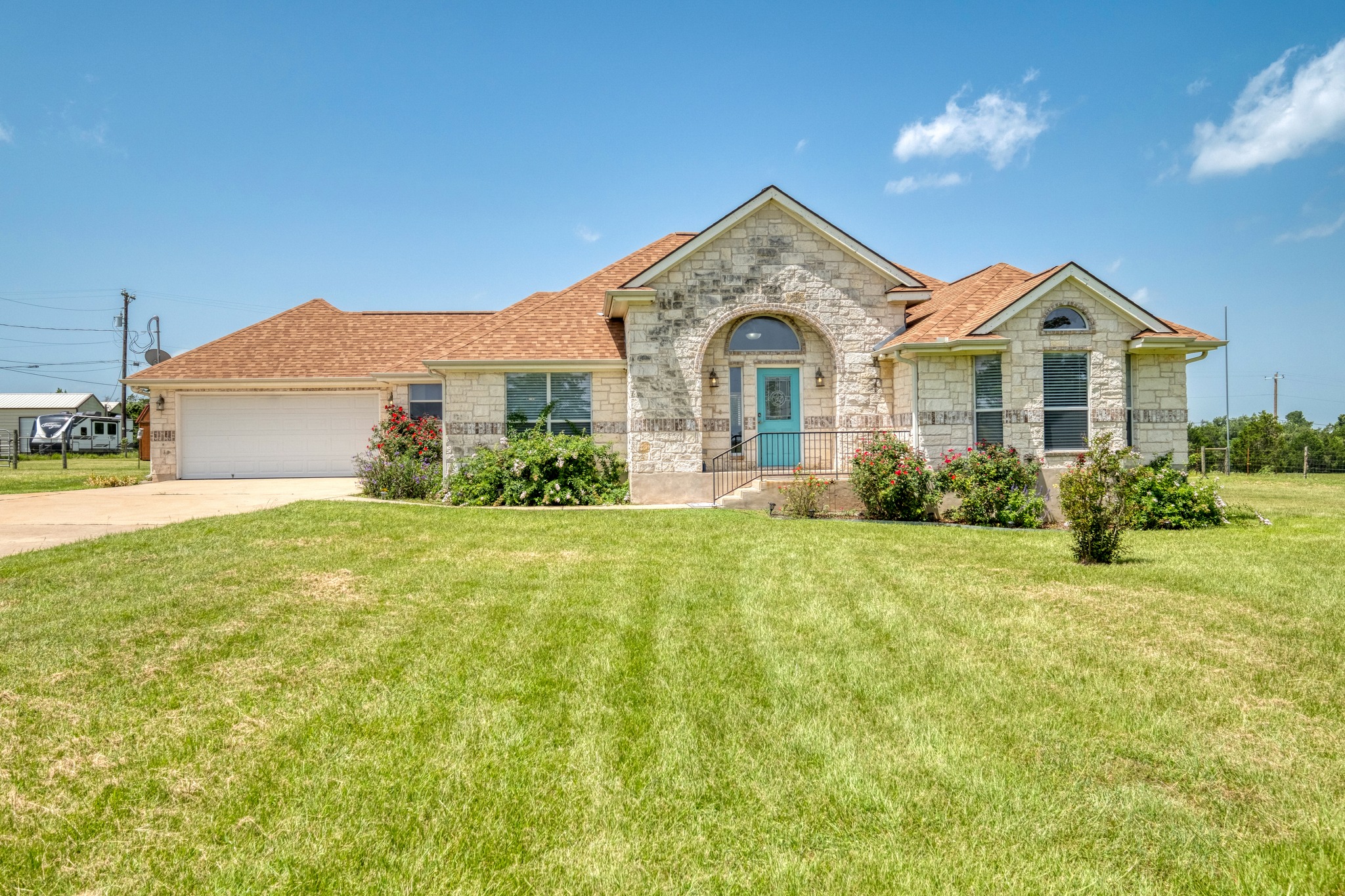 341 Brown Road McDade, TX 78650 - Photo 1 of 38 A well-maintained lawn welcomes visitors to this charming stone-clad residence with a vibrant turquoise front door.