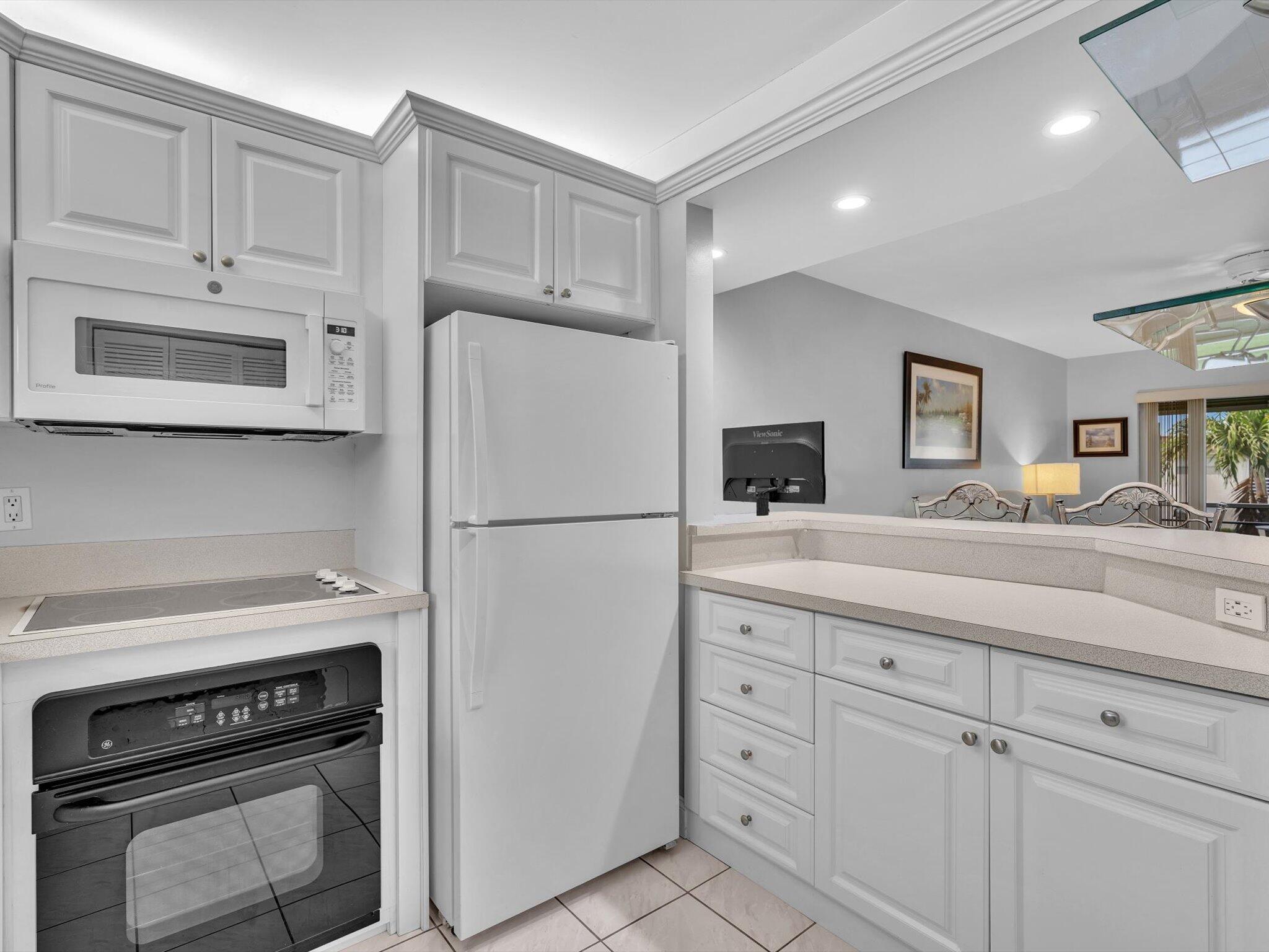 9855 Sandalfoot Boulevard, Unit 320 Boca Raton, FL 33428 - Photo 7 of 23 a kitchen with white cabinets and white appliances