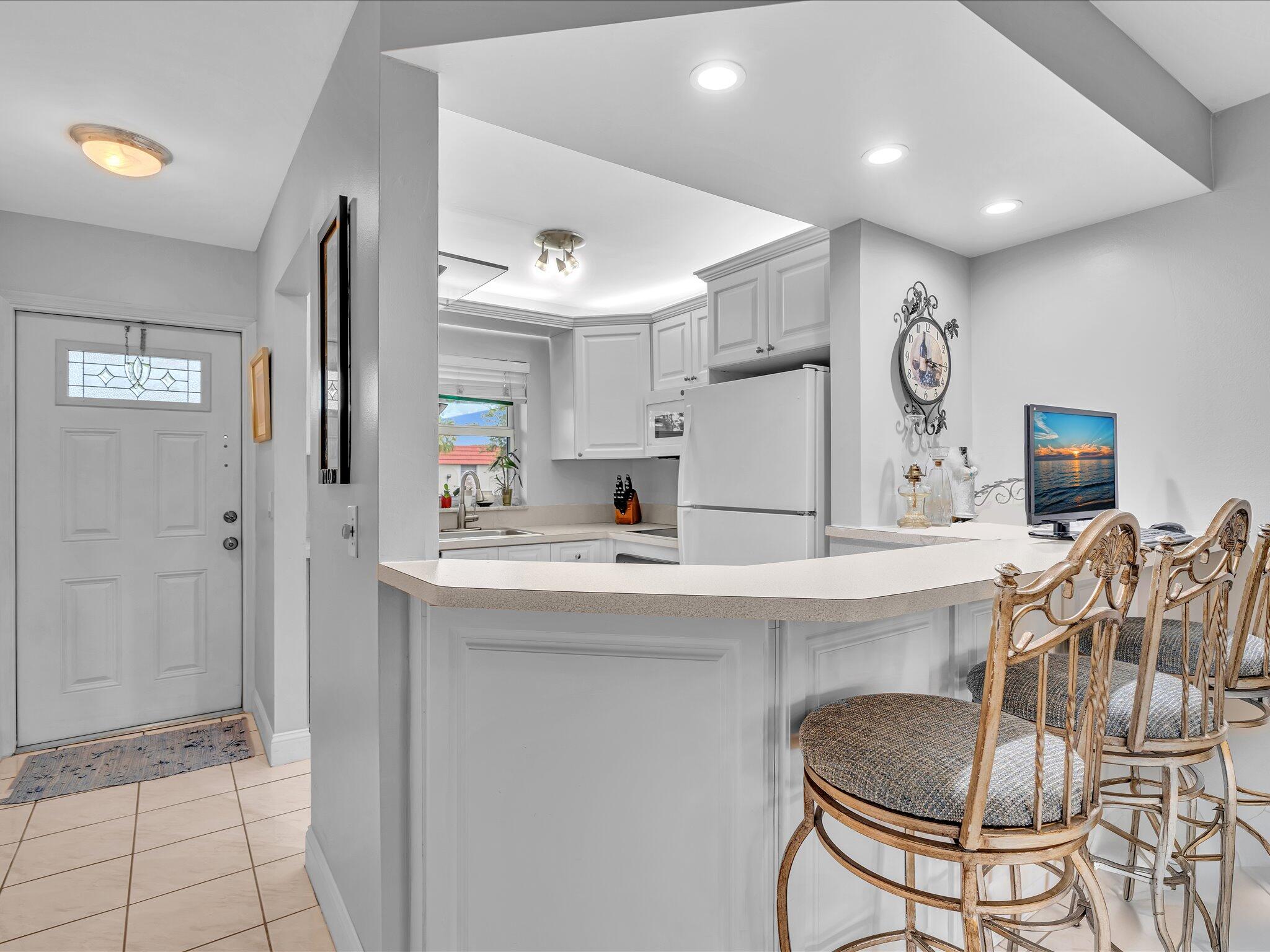 9855 Sandalfoot Boulevard, Unit 320 Boca Raton, FL 33428 - Photo 9 of 23 a kitchen with stainless steel appliances kitchen island granite countertop a refrigerator and a stove top oven