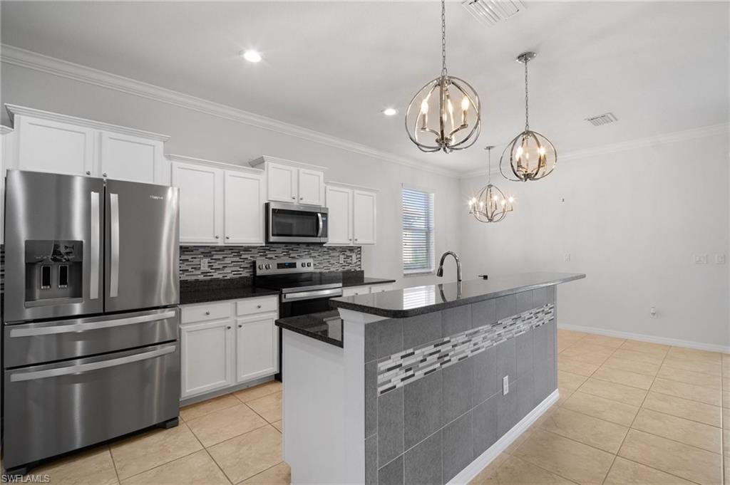 21620 Bella Terra Boulevard Estero, FL 33928 - Photo 3 of 37 a kitchen with stainless steel appliances granite countertop a sink a stove top oven a refrigerator cabinets and chairs