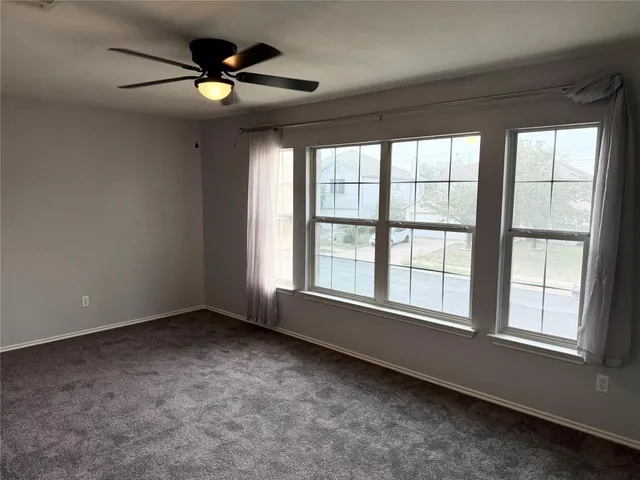 an empty room with chandelier fan and windows