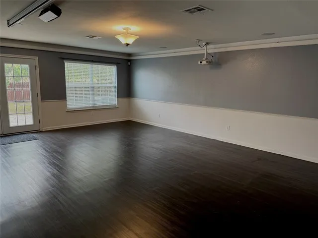 an empty room with wooden floor cabinet and windows