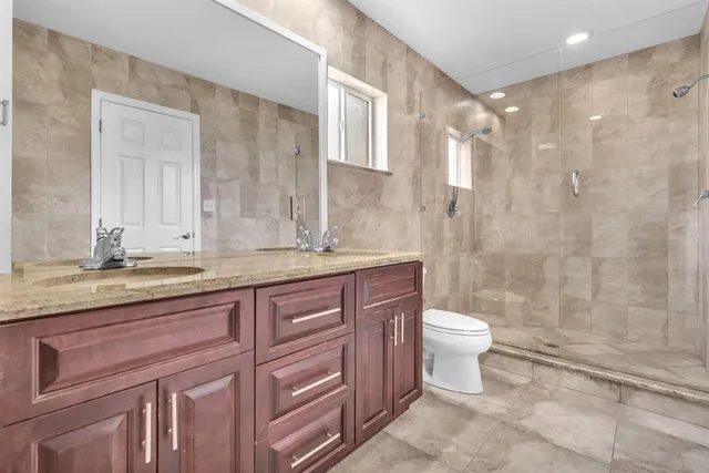 a bathroom with a granite countertop sink toilet and shower