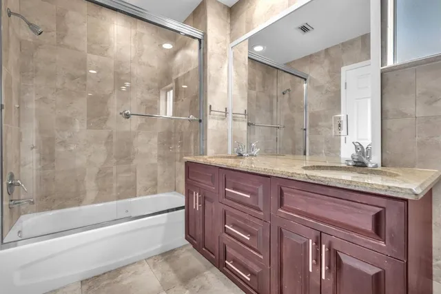 a bathroom with a granite countertop bathtub sink vanity and mirror