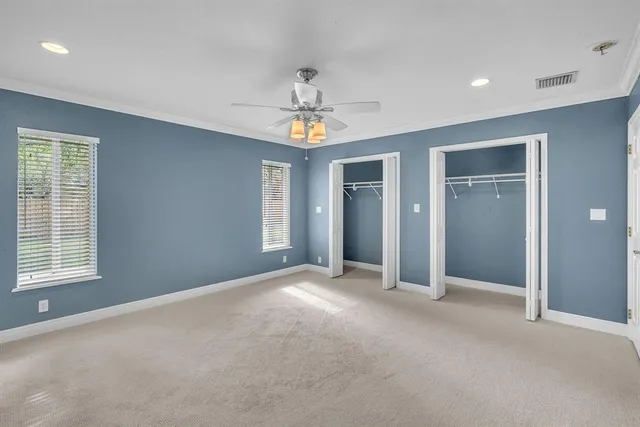 an empty room with chandelier fan and windows