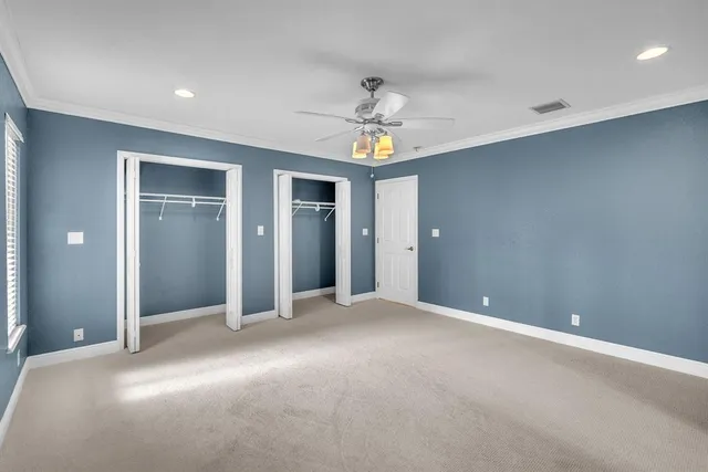 an empty room with chandelier fan and windows