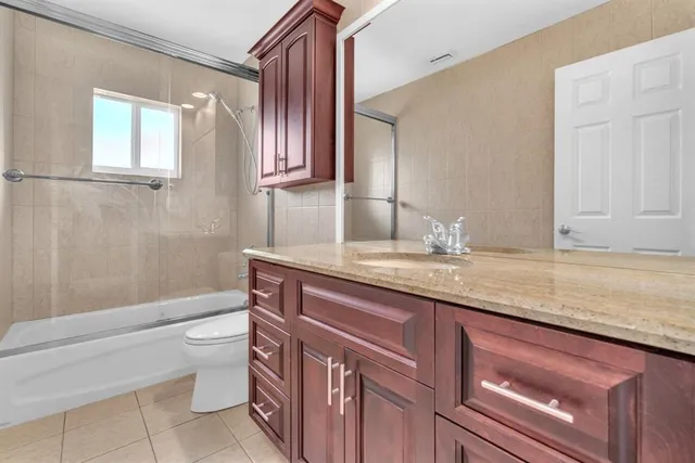 a bathroom with a granite countertop bathtub sink vanity mirror and toilet