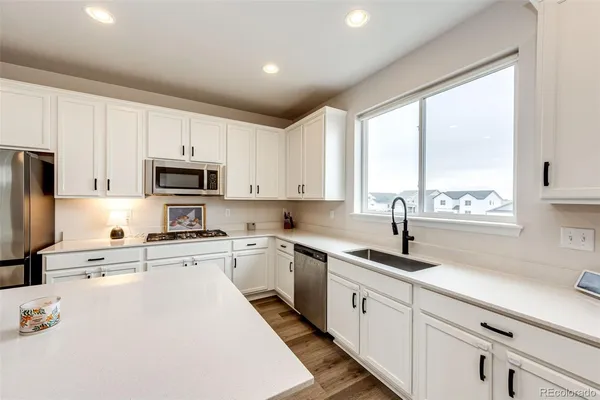 a kitchen with appliances a sink a cabinets and a window