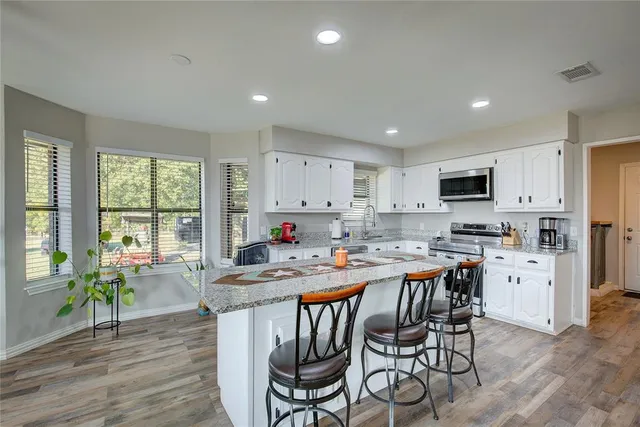 a kitchen with granite countertop a refrigerator a sink a stove and a refrigerator