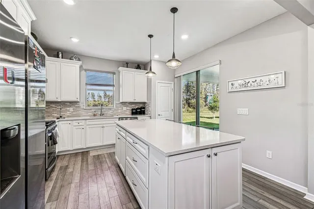 a kitchen with stainless steel appliances kitchen island granite countertop a sink a stove a refrigerator and cabinets