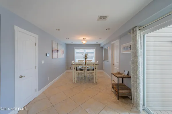 a living room with white couches and kitchen view with wooden floor