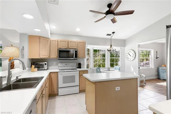 a kitchen with stainless steel appliances kitchen island granite countertop a refrigerator a stove top oven a sink and dishwasher