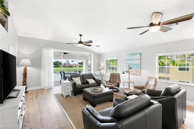 a living room with furniture a flat screen tv and a floor to ceiling window