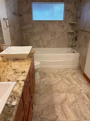a bathroom with a granite countertop sink and a toilet