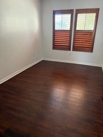 an empty room with wooden floor and mirror