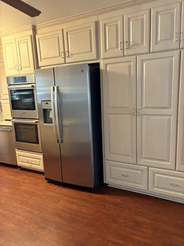 a view of a refrigerator in kitchen and empty room