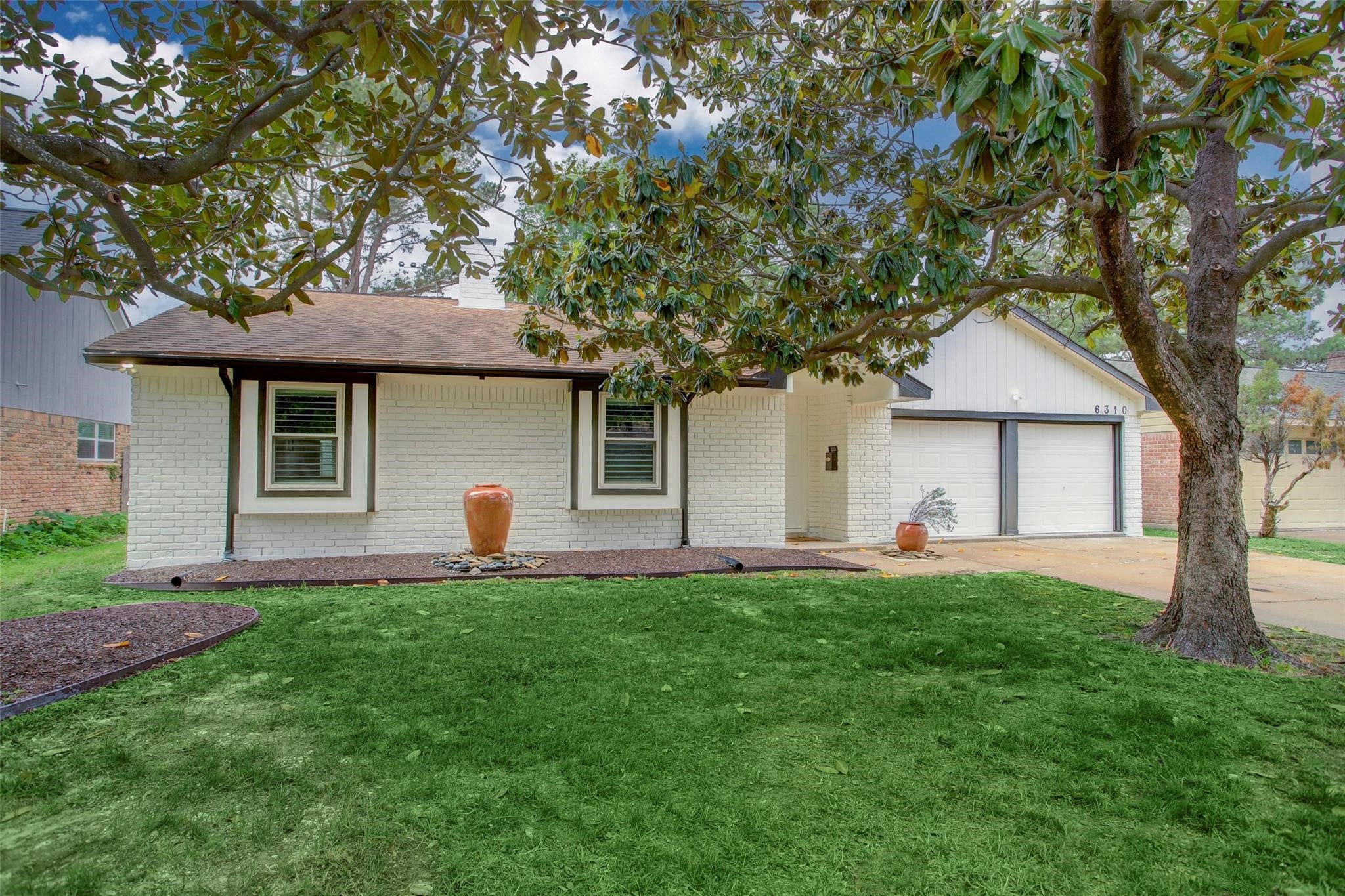 a front view of house with a garden and trees