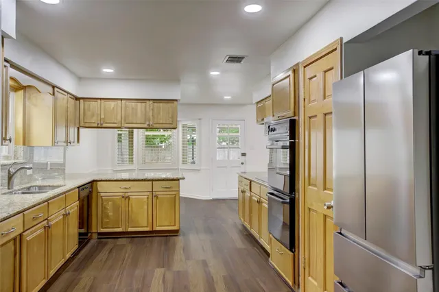 a kitchen with stainless steel appliances a refrigerator a sink cabinets and wooden floor