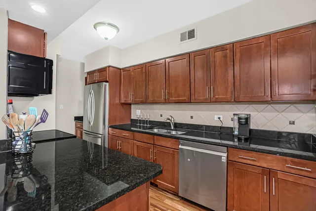 a kitchen with stainless steel appliances granite countertop a sink a stove and a cabinets